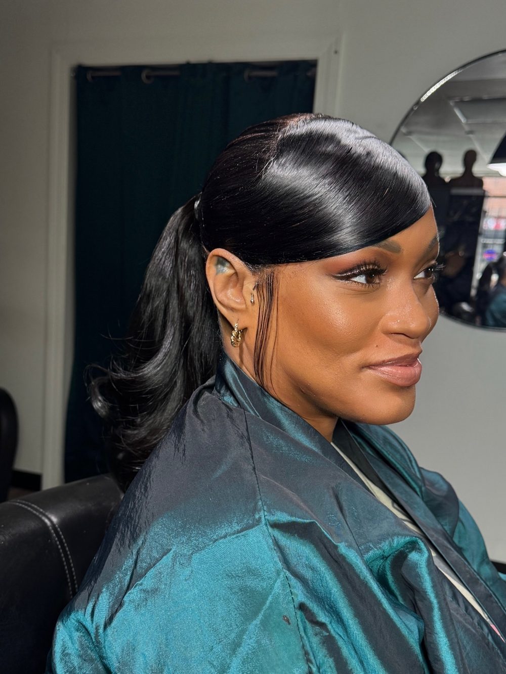 Client sew-in styled into a sleek high ponytail with a side-swept bang and laid edges